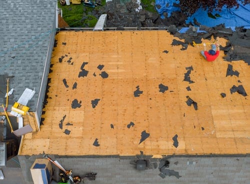 Aerial view of a flat roof section stripped to the decking during a commercial roof restoration project