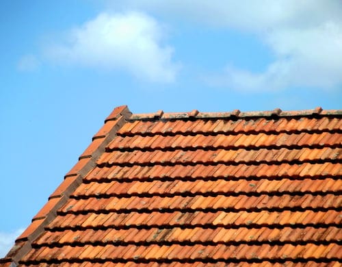 Terracotta tile roof under intense direct sunlight against a clear blue Gulf Coast sky