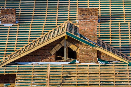 Roof under renovation showing exposed battens, underlayment and framing during a decking replacement