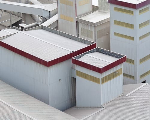 Commercial metal roof panels with red trim viewed from above, a typical candidate for acrylic roof coating