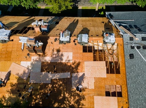 Aerial view of a roofing crew working across a large residential roof deck during an installation